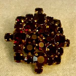 Costume jewelry brooch, gold toned metal, faceted cut red glass, faux gemstones.
